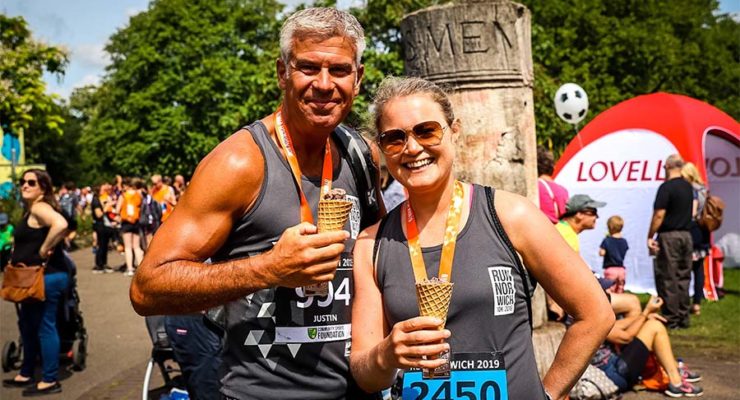 Runners enjoying an ice cream in the race village wearing their finishers medals