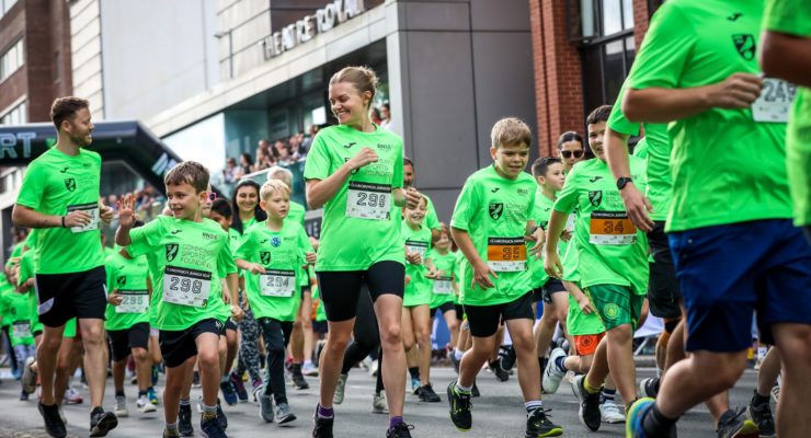 Group of children and woman running in green t shirts