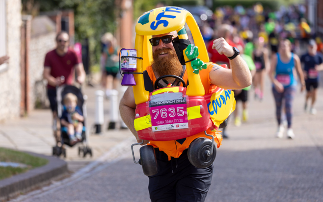man running in a little tike car