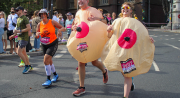 man and woman running in giant inflatable boob costume