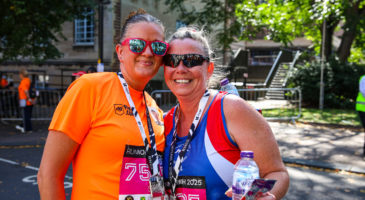 a woman in orange top hugging another woman