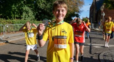 child in yellow tshirt showing off medal