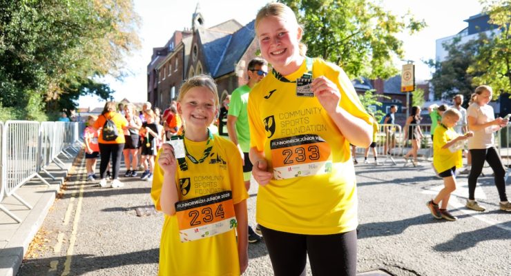 two girls in yellow tshirts showing off medals